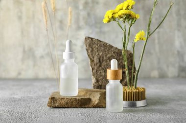 Taşlı kozmetik şişeler ve grunge arkaplanda ikebana.