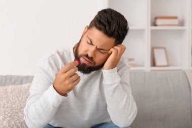 Evde burnu kanayan ve mendili olan sakallı genç bir adam.