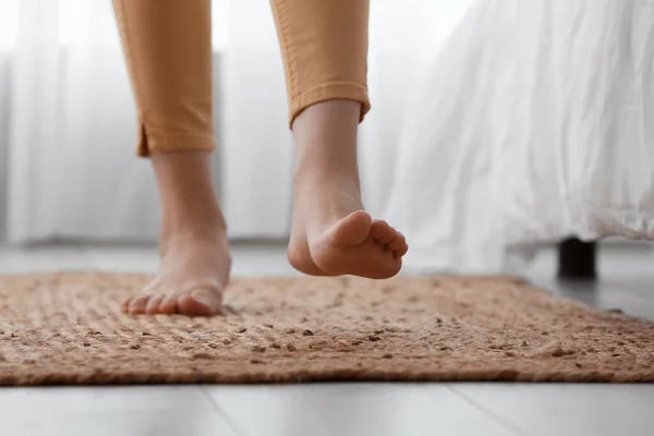 ベッドルームでウィッカーカーペットの上の女性裸の足 クローズアップ — ストック写真