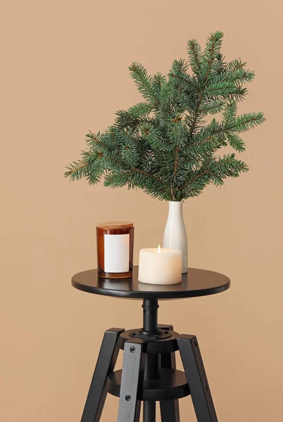 ベージュの壁の近くのテーブルの上にクリスマスの枝や燃えるろうそくと花瓶 — ストック写真
