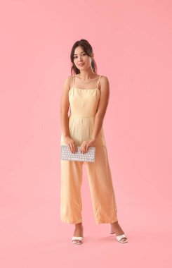 Pembe arka planda bilgisayar klavyesi olan genç Asyalı kadın.