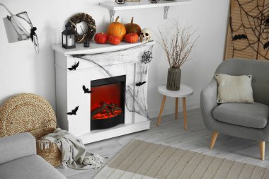 Cadılar Bayramı için dekore edilmiş aydınlık oturma odasının içi şömine, balkabağı ve koltuk ile süslenmiş.