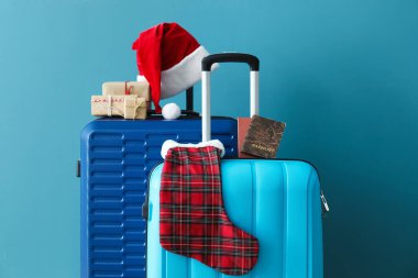 Noel Baba şapkalı bavullar, pasaportlar ve mavi duvarın yanındaki Noel hediyeleri.