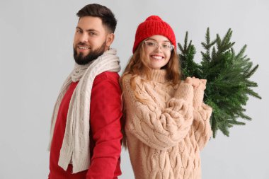 Gri arka planda Noel ağacı olan genç bir çift