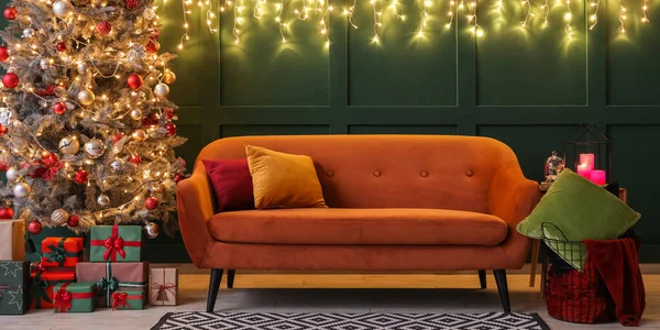 舒适的沙发 房间里有圣诞树 礼物和绿墙边的彩灯 — 图库照片