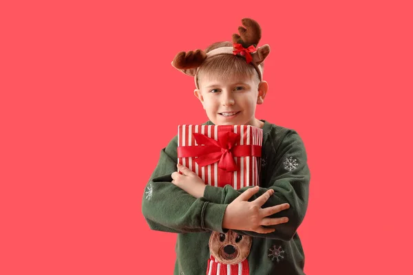 Счастливый Маленький Мальчик Оленьих Рогах Рождественским Подарком Красном Фоне — стоковое фото