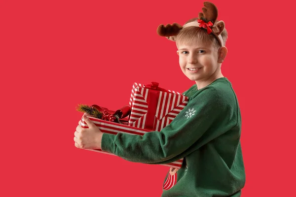 Счастливый Маленький Мальчик Оленьих Рогах Рождественскими Подарками Красном Фоне — стоковое фото