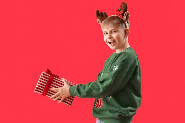 Kırmızı Arka Planda Noel Hediyesi Olan Ren Geyiği Boynuzlu Mutlu — Stok fotoğraf