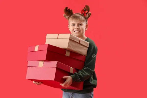 Glücklicher Kleiner Junge Rentierhörnern Mit Weihnachtsgeschenken Auf Rotem Hintergrund — Stockfoto