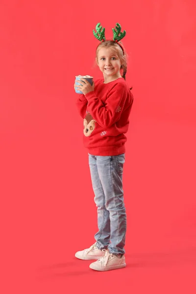 Ευτυχισμένο Κοριτσάκι Κέρατα Ταράνδου Ένα Φλιτζάνι Κακάο Κόκκινο Φόντο — Φωτογραφία Αρχείου
