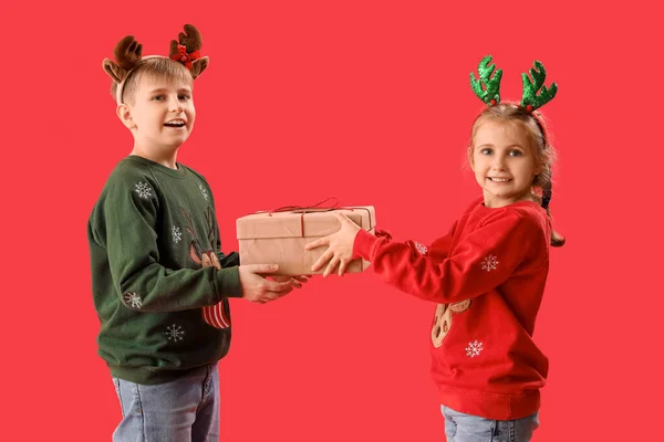 Glückliche Kleine Kinder Rentierhörnern Mit Weihnachtsgeschenk Auf Rotem Hintergrund — Stockfoto