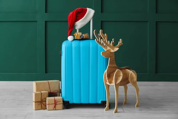 Koffer Met Kerstmuts Kerstcadeaus Houten Rendieren Bij Groene Muur — Stockfoto