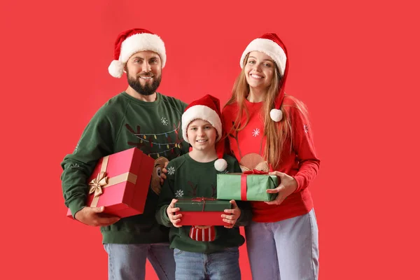 Mutlu Ebeveynler Noel Baba Şapkalı Küçük Oğulları Kırmızı Arka Planda — Stok fotoğraf