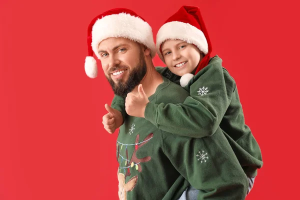 幸せな父とともに彼の小さな息子でサンタ帽子ショー親指アップ上の赤い背景 — ストック写真