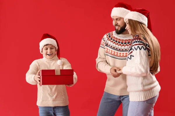 Petit Garçon Avec Cadeau Noël Ses Parents Sur Fond Rouge — Photo