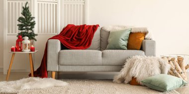 Oturma odasının içinde kanepe ve masasında küçük ağaç olan Noel fenerleri var.