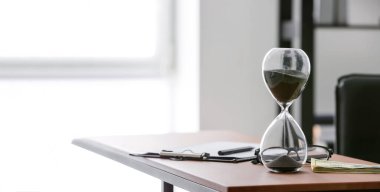 Ofisteki masasında dolar banknotları olan kum saati. Vakit nakittir.