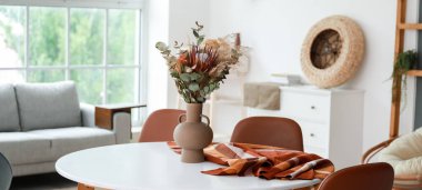 Odadaki masanın üstünde kurumuş çiçek dekoru olan vazo.