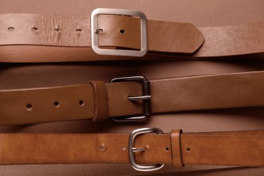 Kahverengi arka planda tokaları olan deri kemerler.