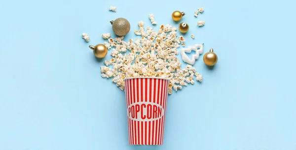 stock image Bucket of popcorn and Christmas balls on light blue background