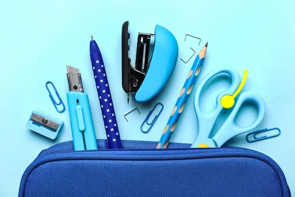 Stylish pencil case with different stationery on color background, closeup