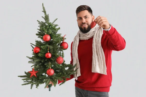 クリスマスツリーとグレーの背景の装飾を持つハンサムな男 — ストック写真