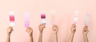 Pembe arka planda farklı renk desenleri tutan kadın elleri