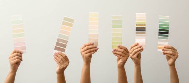 Işık arkaplan üzerinde farklı renk desenleri tutan kadın eller