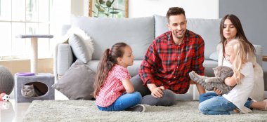 Mutlu aile evde sevimli kedilerle oynuyor.