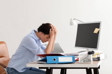 Ofiste oturan stresli genç iş kadını.