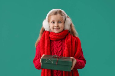 Yeşil arka planda Noel hediyesi olan kulaklı küçük bir kız.