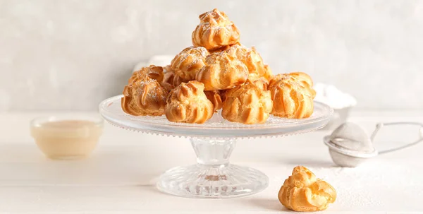 stock image Dessert stand with delicious profiteroles on light table