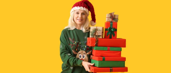 Volwassen Vrouw Met Veel Kerstcadeau Dozen Gele Achtergrond — Stockfoto