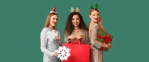 緑の背景にクリスマスプレゼント ショッピングバッグや装飾を持つ美しい若い女性 — ストック写真