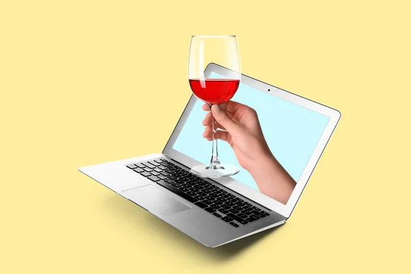 Sarı Arka Plandaki Dizüstü Bilgisayardan Kırmızı Şarap Kadehini Tutan Kadın — Stok fotoğraf