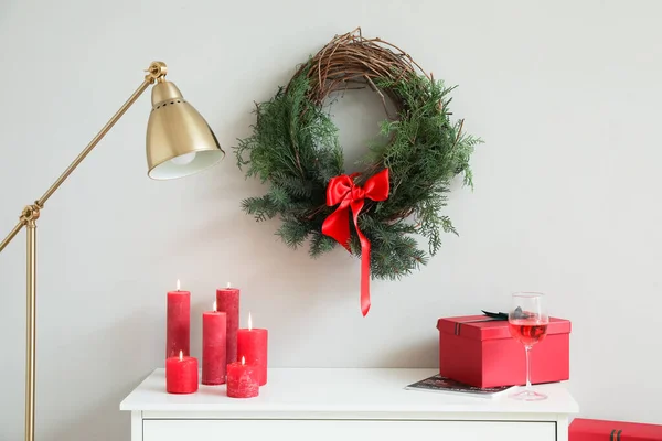 桌上放着燃烧的蜡烛 圣诞礼物和挂在轻墙上的花环 — 图库照片