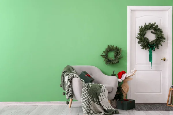 Białe Drzwi Wieńcem Bożonarodzeniowym Drewnianym Reniferem Fotelem Przy Zielonej Ścianie — Zdjęcie stockowe