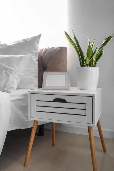 光の寝室の写真フレームと観葉植物とベッドサイドテーブル — ストック写真