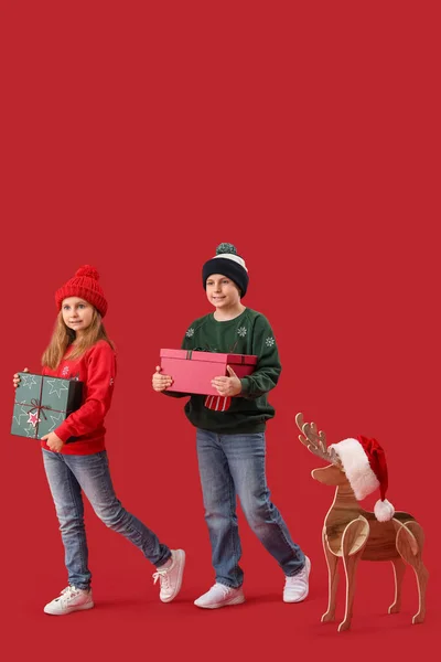 Niños Pequeños Con Regalos Navidad Renos Madera Sobre Fondo Rojo — Foto de Stock