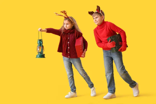 Małe Dzieci Rogach Reniferów Prezentami Świątecznymi Latarnią Żółtym Tle — Zdjęcie stockowe