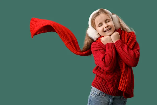 小さな女の子でEarmuffと暖かいスカーフで緑の背景 — ストック写真