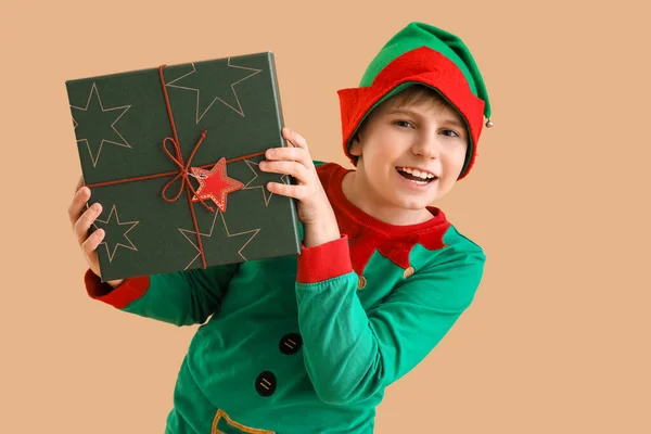 stock image Little boy dressed as elf with Christmas gift on beige background
