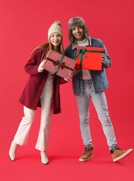 Ευτυχισμένο Νεαρό Ζευγάρι Χριστουγεννιάτικα Δώρα Κόκκινο Φόντο — Φωτογραφία Αρχείου