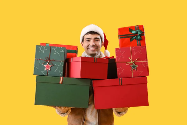 Happy Young Man Santa Hat Christmas Gifts Yellow Background — Stock Photo, Image