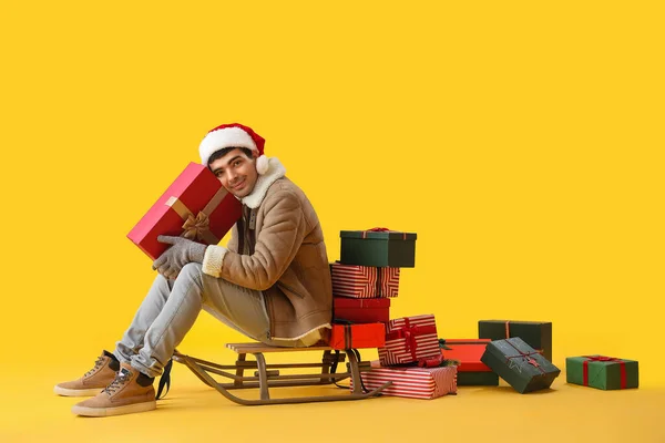 Young Man Santa Hat Christmas Gifts Sledge Yellow Background — Stock Photo, Image