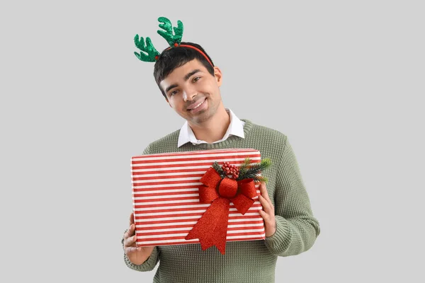 Молодой Человек Оленьих Рогах Рождественским Подарком Сером Фоне — стоковое фото