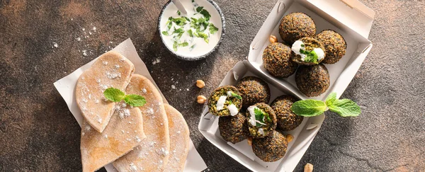 stock image Boxes with tasty falafel balls, pitas and sauce on grunge background