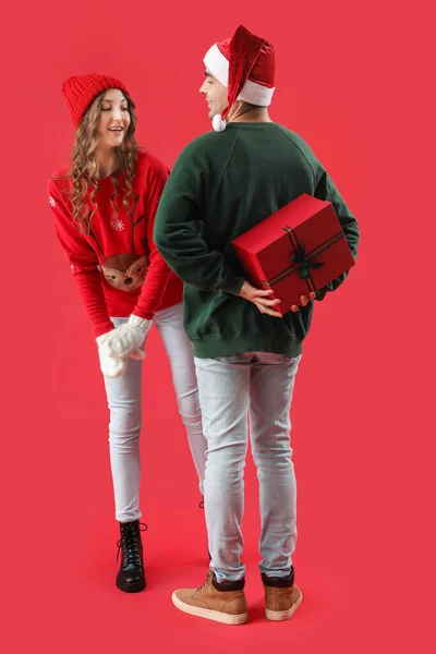 Fiatal Férfi Meglepi Szeretett Barátnője Karácsonyi Ajándék Piros Háttér — Stock Fotó