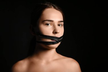 Ağzında fermuarı koyu arka planda olan genç bir kadın. Sansür kavramı