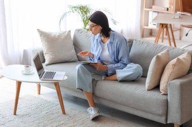 Kadın psikolog evdeki kanepede hastayla sohbet ediyor.